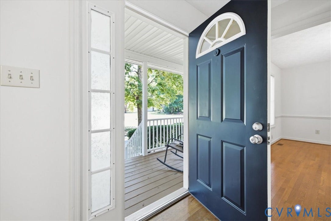 Front entry featuring a dark blue paneled door with an arched transom window, a sidelight with textured glass.