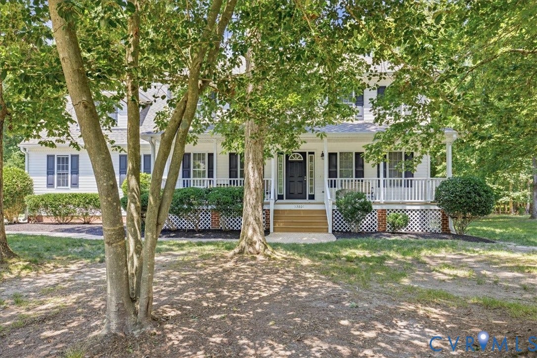 White siding residence featuring a welcoming covered front porch with white railings, dark shutters, and a dark front door