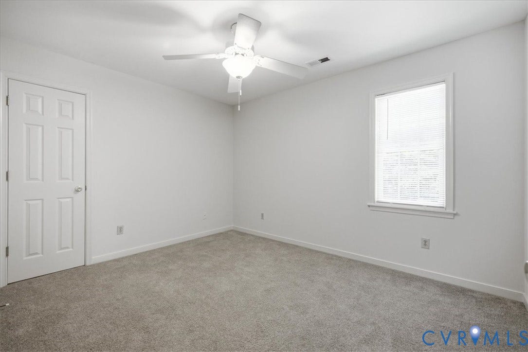 Carpeted bedroom #2 featuring a ceiling fan with integrated lighting, a paneled door to a closet, and a window with blinds