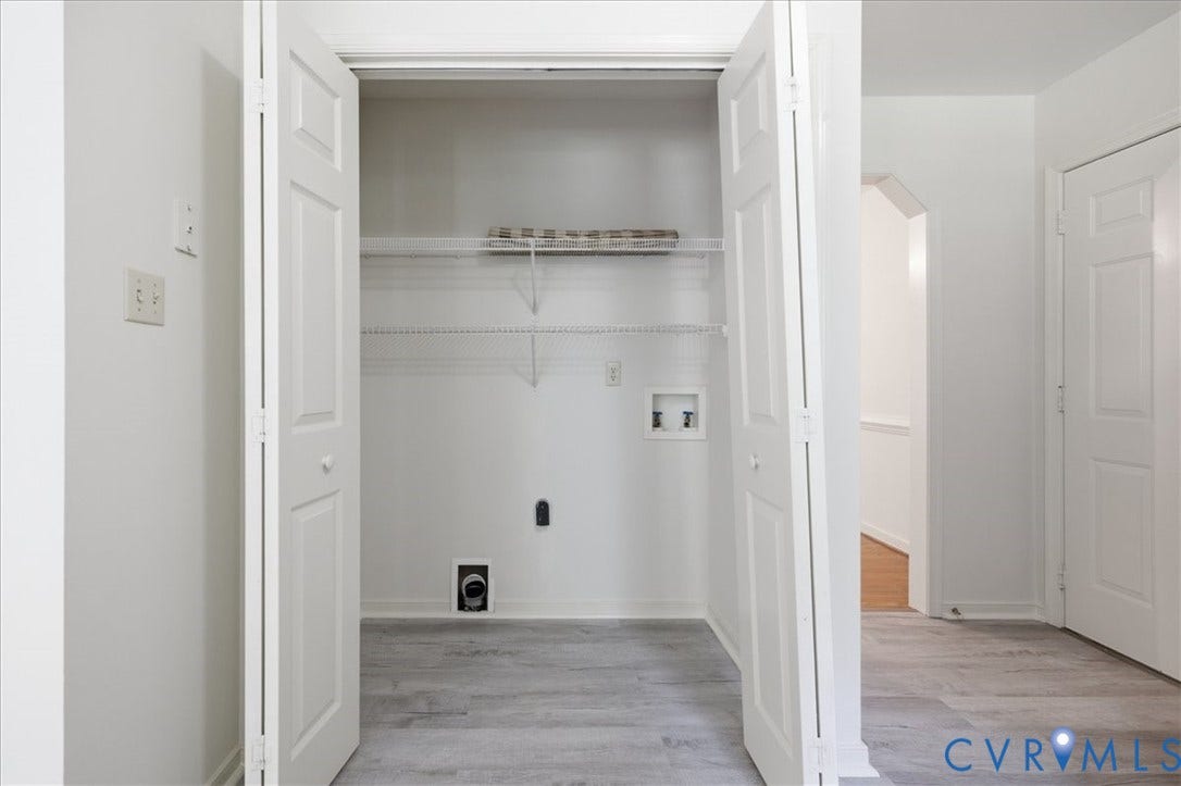Laundry closet with bi-fold doors, new grey LVP flooring, and wire shelving