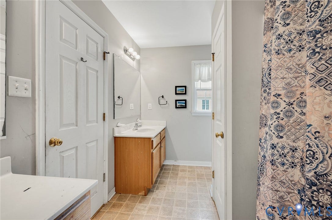 1207 Wycliff Court, Richmond, VA 23236 Bathroom featuring a single vanity with a laminate countertop, light wood-finish cabinetry, and a mirrored wall