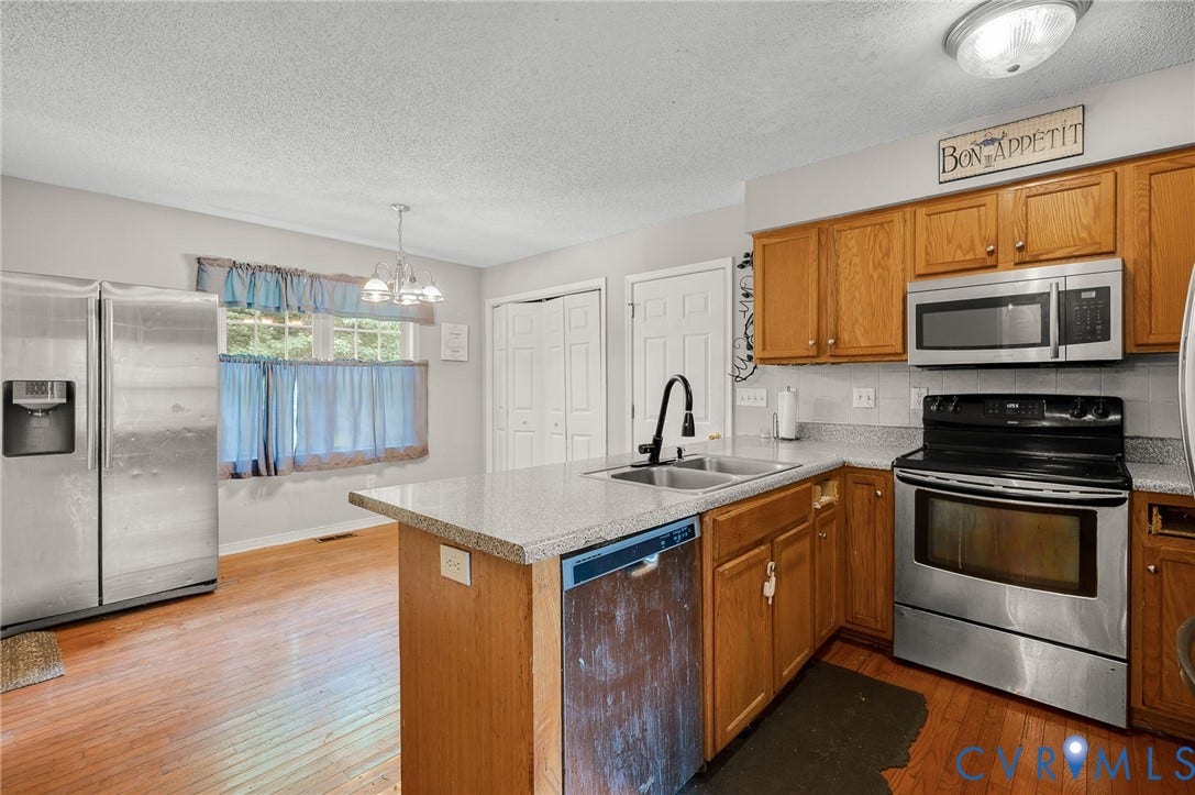 1207 Wycliff Court, Richmond, VA 23236 Kitchen featuring wood-finish flooring, stainless steel appliances, light-toned cabinetry, light-toned countertops, and a double-basin sink with a matte black faucet