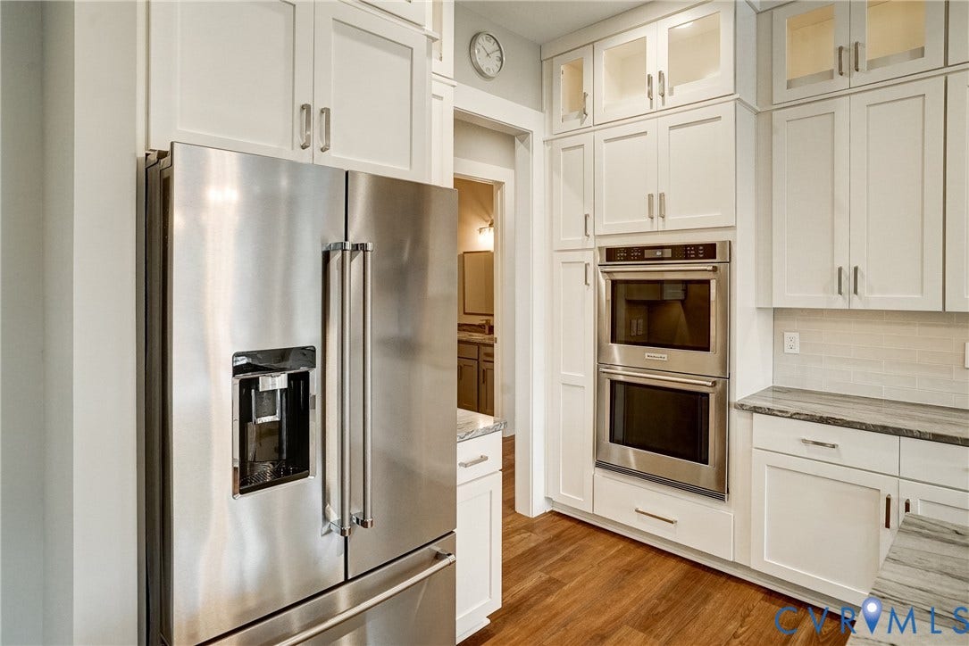 1732 Fishers Pond Drive, Maidens, VA 23102 Kitchen featuring stainless steel appliances, white cabinetry with upper glass-front cabinets, wood-finish flooring, a stacked double oven, and a refrigerator with a water/ice dispenser