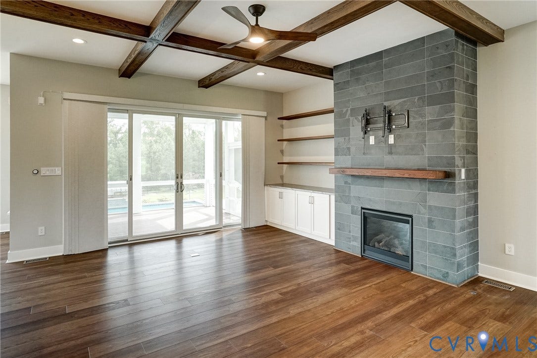1732 Fishers Pond Drive, Maidens, VA 23102 Living area featuring wood-finish flooring, a contemporary fireplace with a stone surround and wood mantel, exposed ceiling beams, and integrated ceiling fan