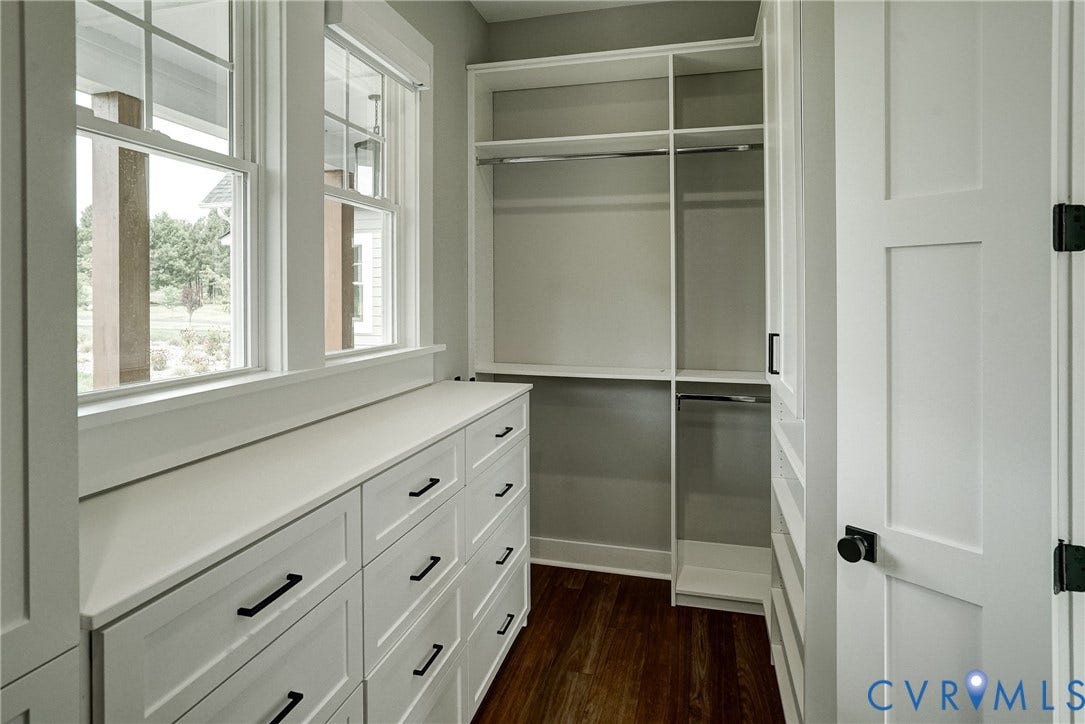 1732 Fishers Pond Drive, Maidens, VA 23102 Custom closet system featuring built-in white cabinetry, multiple drawers with dark hardware, and integrated shelving with hanging rods