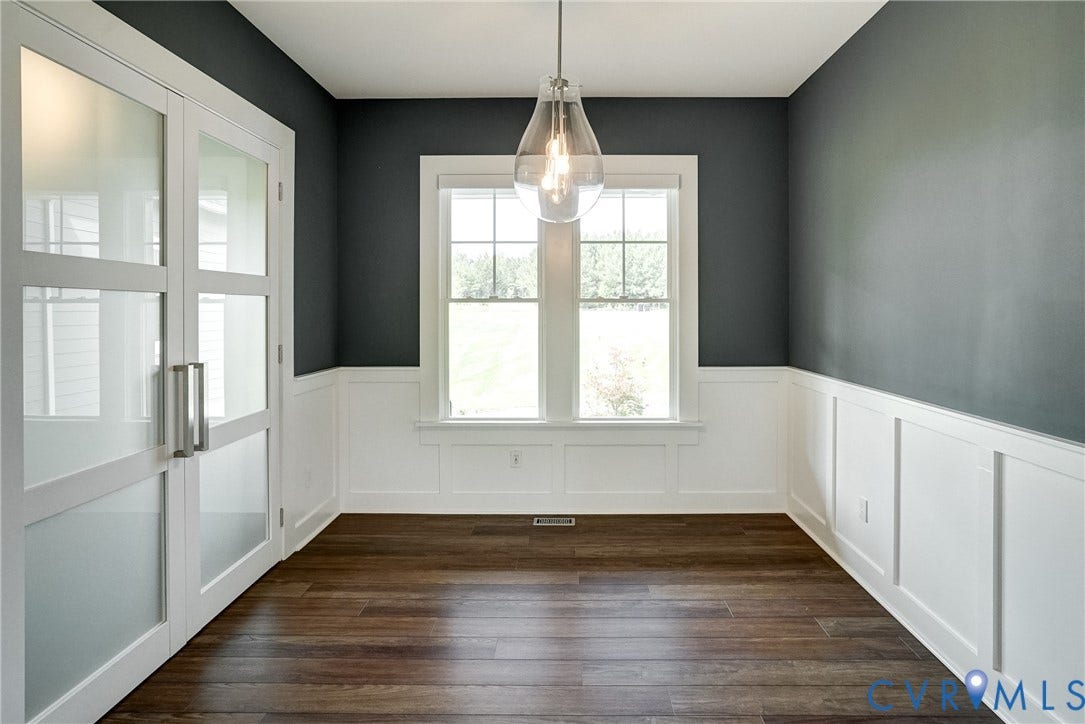 1732 Fishers Pond Drive, Maidens, VA 23102 Room featuring wood-finish flooring, a contemporary pendant light fixture, wainscoting details, a double window, and frosted glass French doors with brushed nickel hardware