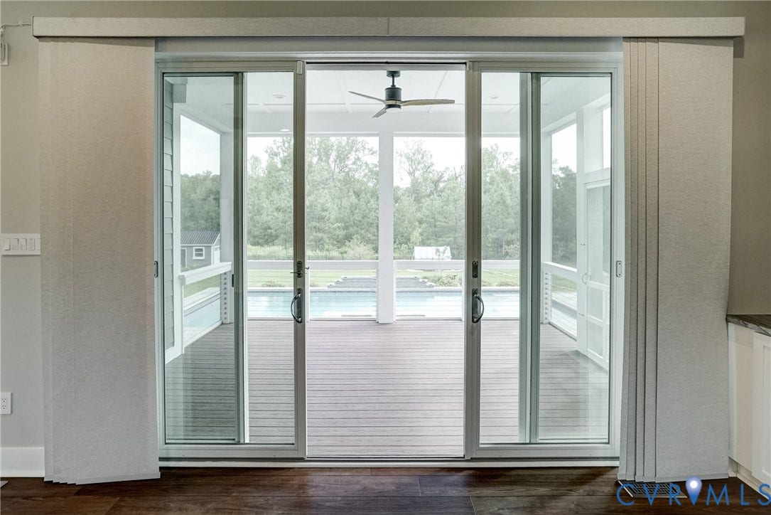 1732 Fishers Pond Drive, Maidens, VA 23102 Sliding glass doors featuring vertical blinds opening to a screened porch with a ceiling fan, wood-finish flooring, and a swimming pool beyond