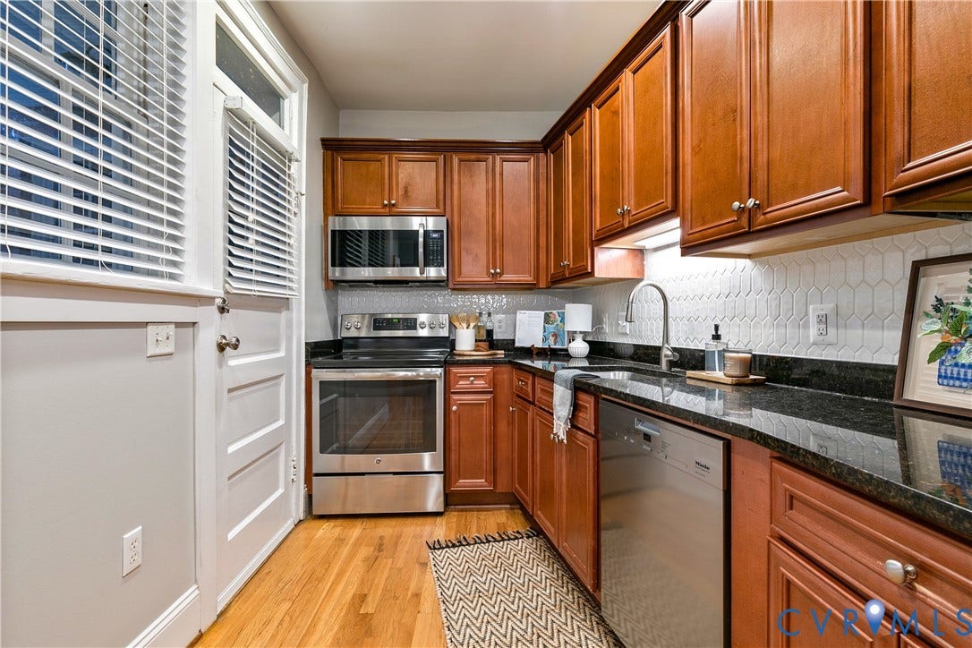 601 Roseneath Road, #U1, Museum District, Richmond, VA 23221 Kitchen featuring wood-finish cabinetry, dark countertops, a white picket tile backsplash, stainless steel appliances, and wood-finish flooring