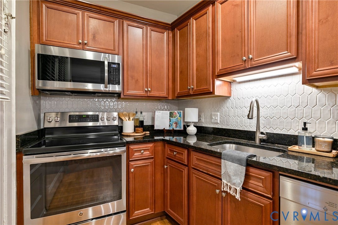 601 Roseneath Road, #U1, Museum District, Richmond, VA 23221 Kitchen featuring wood-finish cabinetry, black countertops, and a mosaic tile backsplash