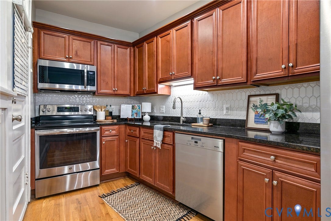 601 Roseneath Road, #U1, Museum District, Richmond, VA 23221 Kitchen featuring wood-finish cabinetry, dark countertops, white geometric tile backsplash, and stainless steel appliances including a range, microwave, and dishwasher