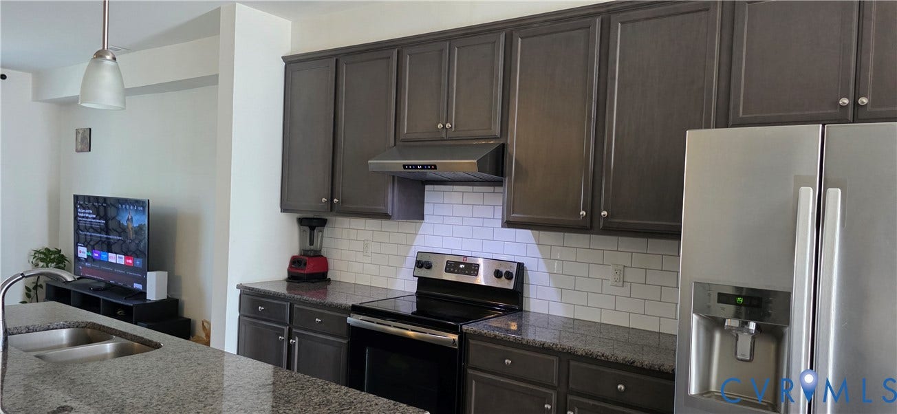 Kitchen featuring dark wood-finish cabinetry, granite countertops, and a white subway tile backsplash