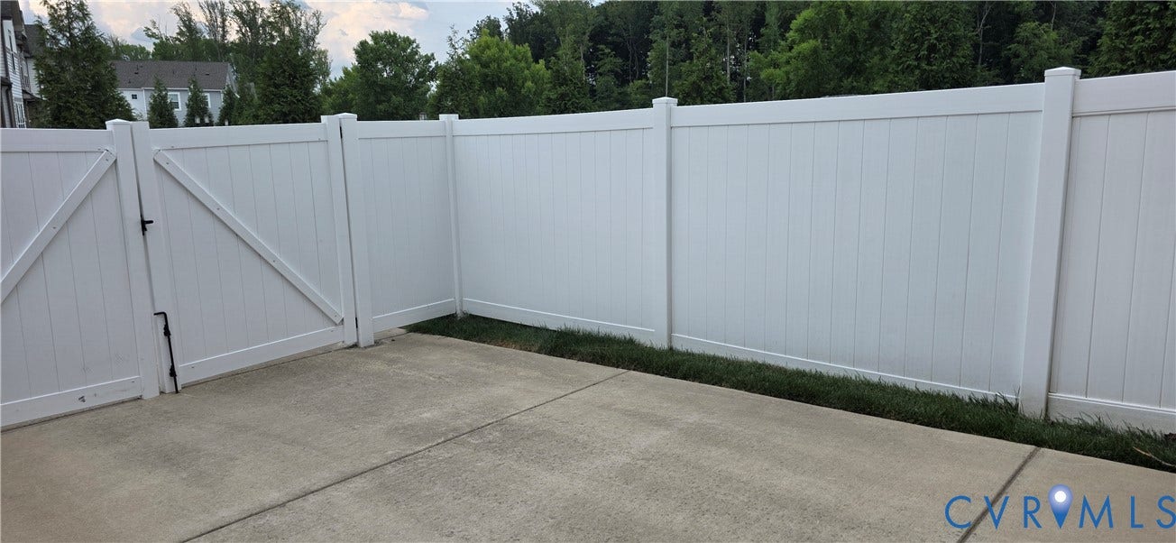 Concrete patio area featuring a privacy fence with a gate