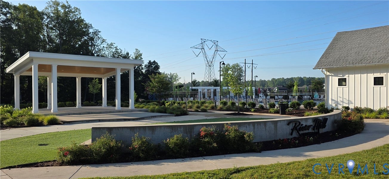 Community amenity area featuring a white columned pavilion, a structured hardscape with a low retaining wall, and manicured landscaping