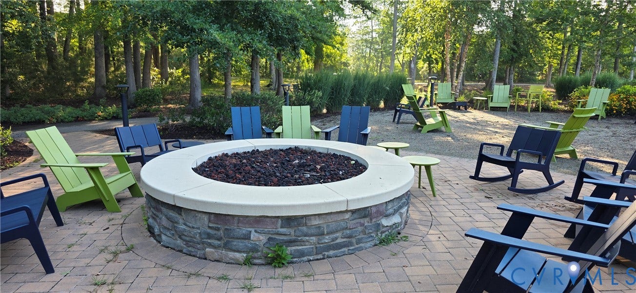 Circular stone fire pit with a light-colored cap, surrounded by a paver patio