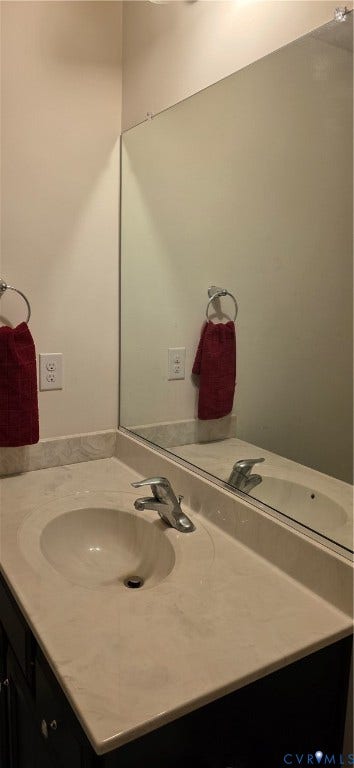 Vanity featuring an integrated sink, polished chrome faucet, and expansive wall-mounted mirror