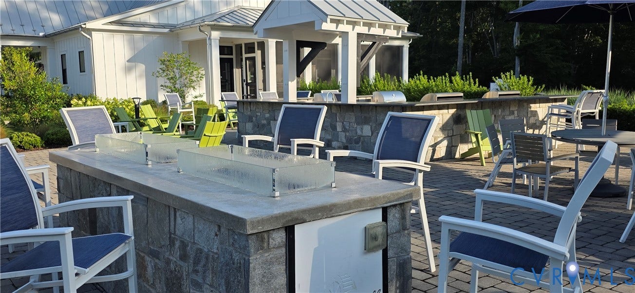 Outdoor entertainment area featuring a stone block fire pit with a concrete top, integrated grilling stations, and a paver patio