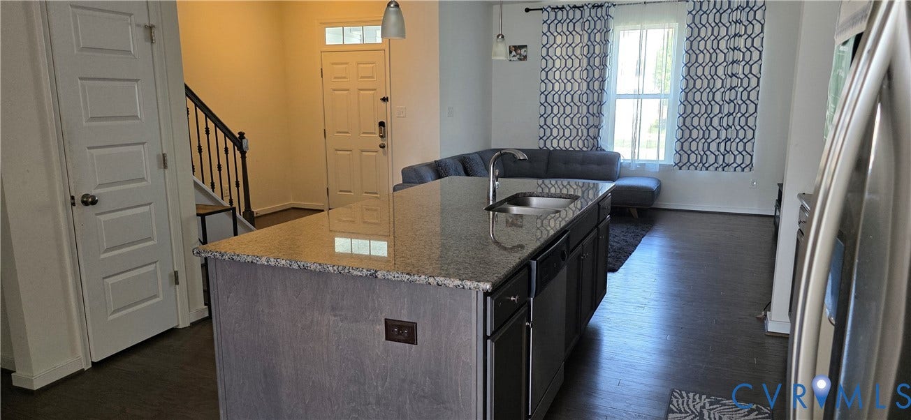 Open-concept kitchen featuring a spacious island with a double basin sink and stone countertop