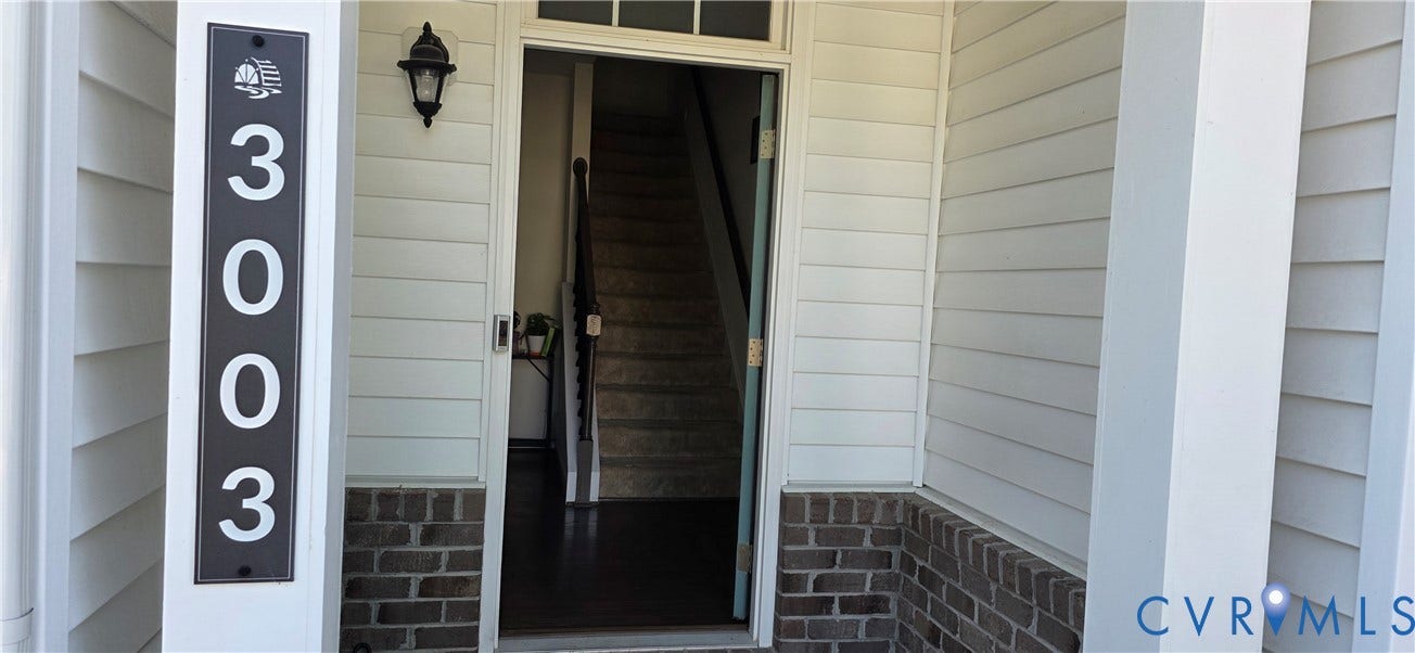 Inviting entryway featuring white horizontal siding and a brick foundation