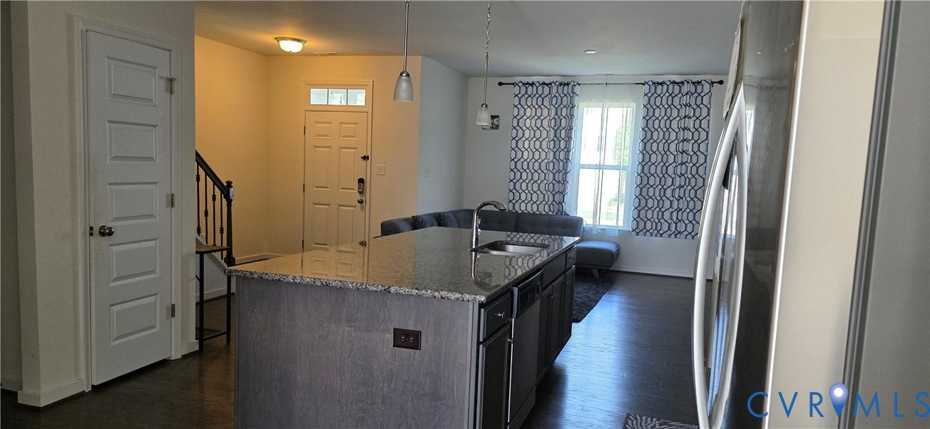 Kitchen island featuring a granite countertop, undermount sink, and two pendant light fixtures
