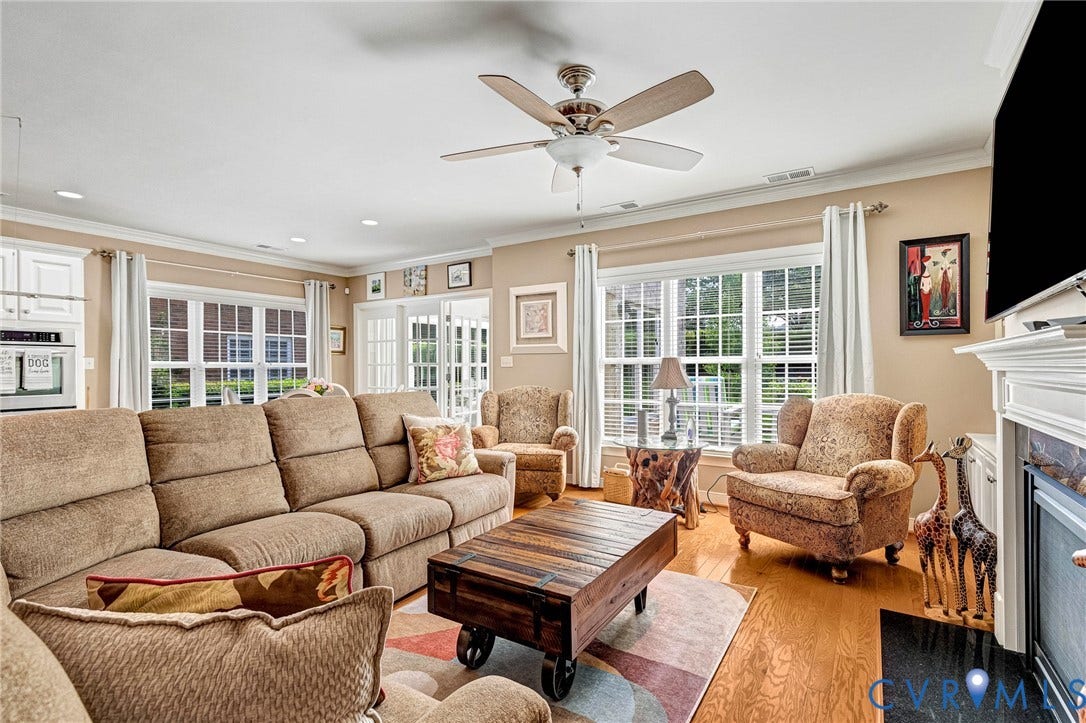 1020 Belva Court, Glen Allen, VA 23059 Spacious living area featuring warm wood-finish flooring, a ceiling fan, and abundant natural light from multiple windows