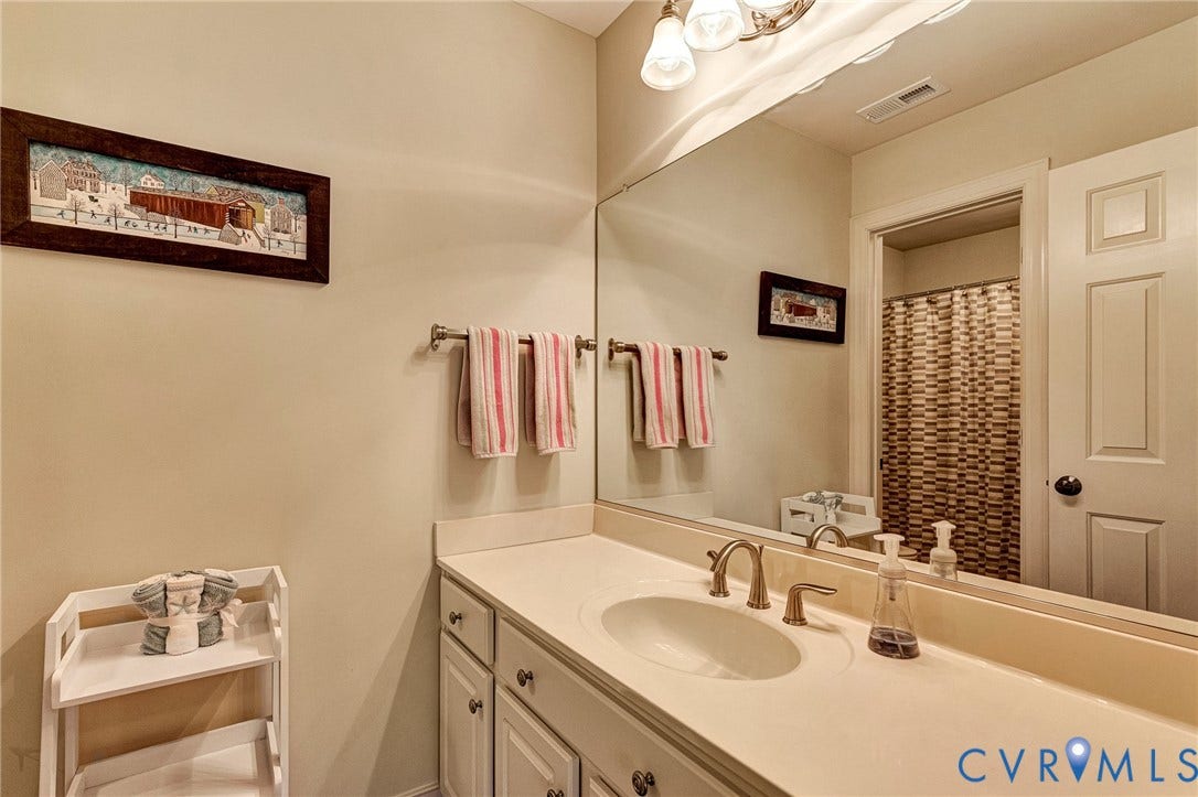 1020 Belva Court, Glen Allen, VA 23059 Bathroom vanity featuring an integrated sink, brushed brass-finish faucet, and a wall-mounted mirror