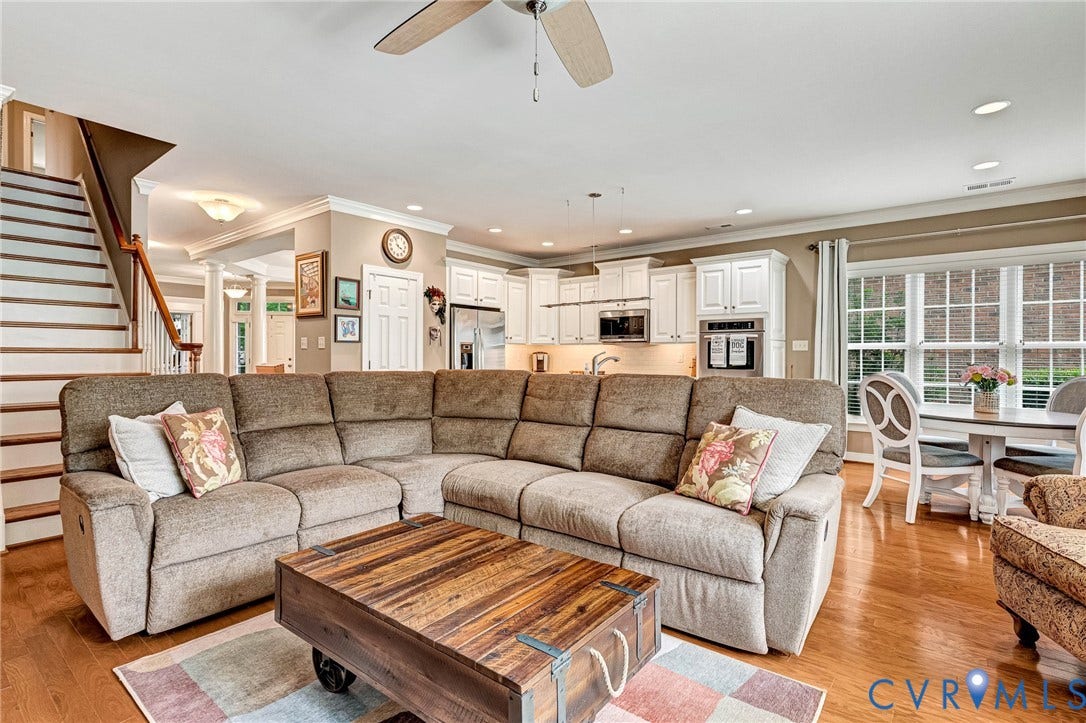 1020 Belva Court, Glen Allen, VA 23059 Open-concept living area featuring wood-finish flooring throughout, a staircase with wood railing, a kitchen with white cabinetry, a built-in oven, and a dining area with a window