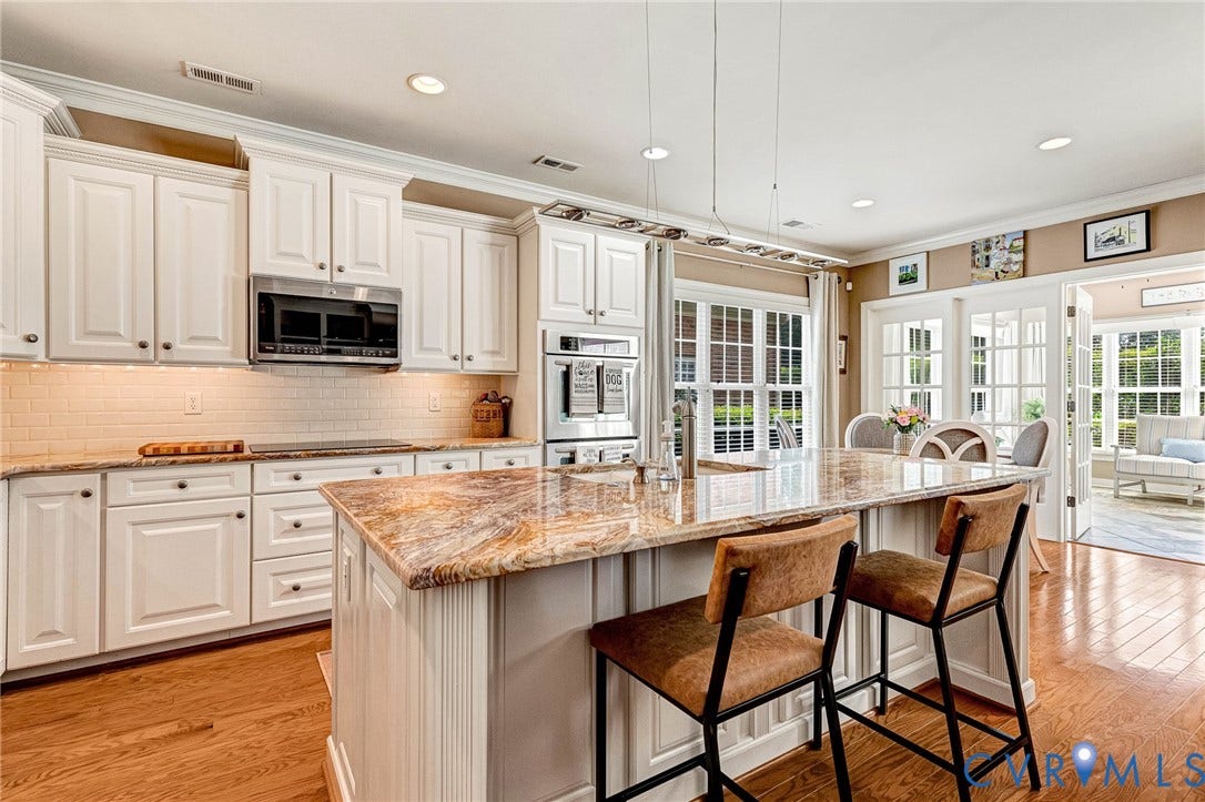1020 Belva Court, Glen Allen, VA 23059 Gourmet kitchen featuring a large central island with a stone countertop, white cabinetry, integrated stainless steel appliances, hardwood flooring, and French doors leading to an additional room