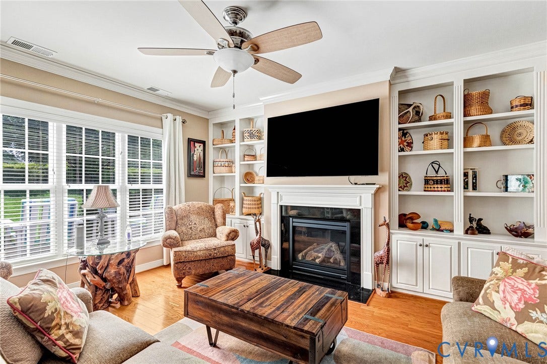 1020 Belva Court, Glen Allen, VA 23059 Living area featuring a gas fireplace with a white mantel and black surround, flanked by built-in white shelving and cabinetry