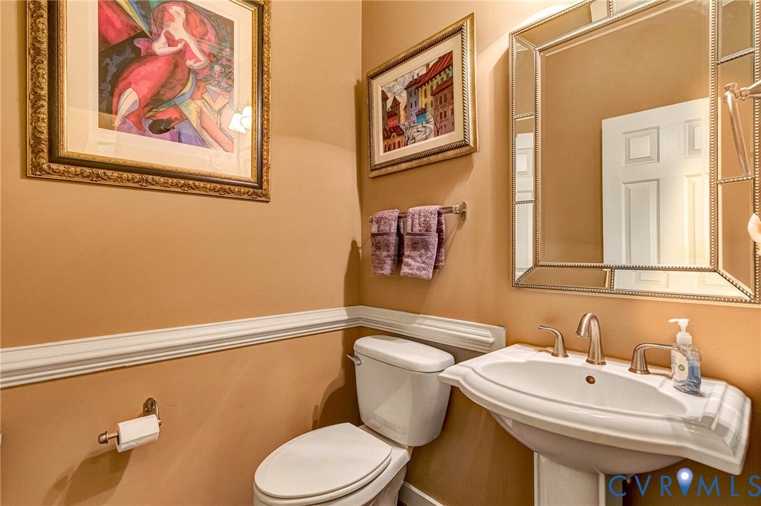 1020 Belva Court, Glen Allen, VA 23059 Pedestal sink with brushed nickel faucet, mirror with a decorative frame, chair rail molding, and neutral wall color