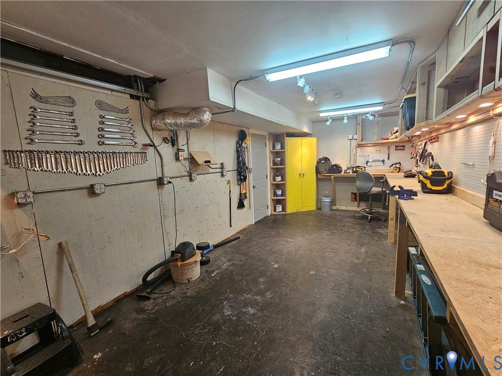 14600 Ramblewood Drive, Chester, VA 23836 Concrete flooring, built-in workbench, overhead fluorescent lighting, exposed conduit, and wall-mounted storage cabinet