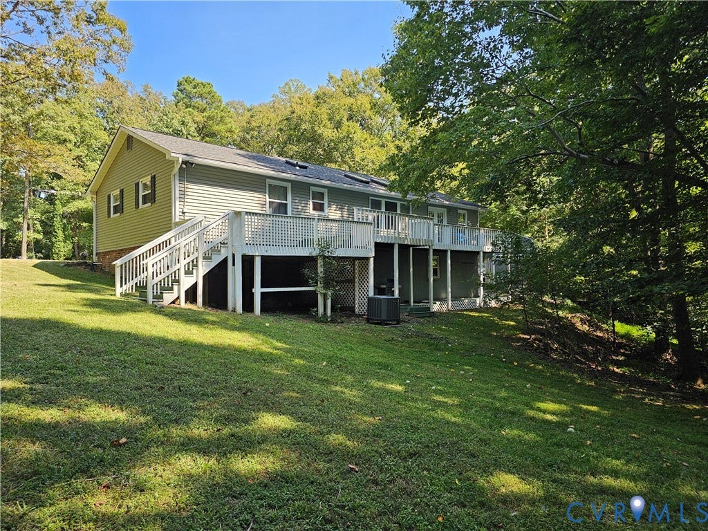 14600 Ramblewood Drive, Chester, VA 23836 Two-story residence with light green siding and dark shutters, featuring a multi-level wooden deck with white railings