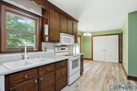 2804 Executive Drive, John Tyler Woods, Chester, VA 23831 Kitchen featuring dark wood cabinetry, white appliances, a double basin sink, and a window with exterior views