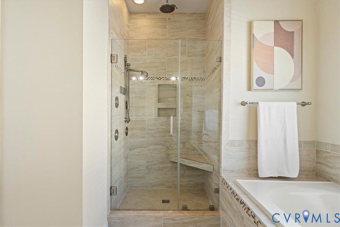 Glass-enclosed shower with a built-in bench, multiple shower heads, and an integrated niche