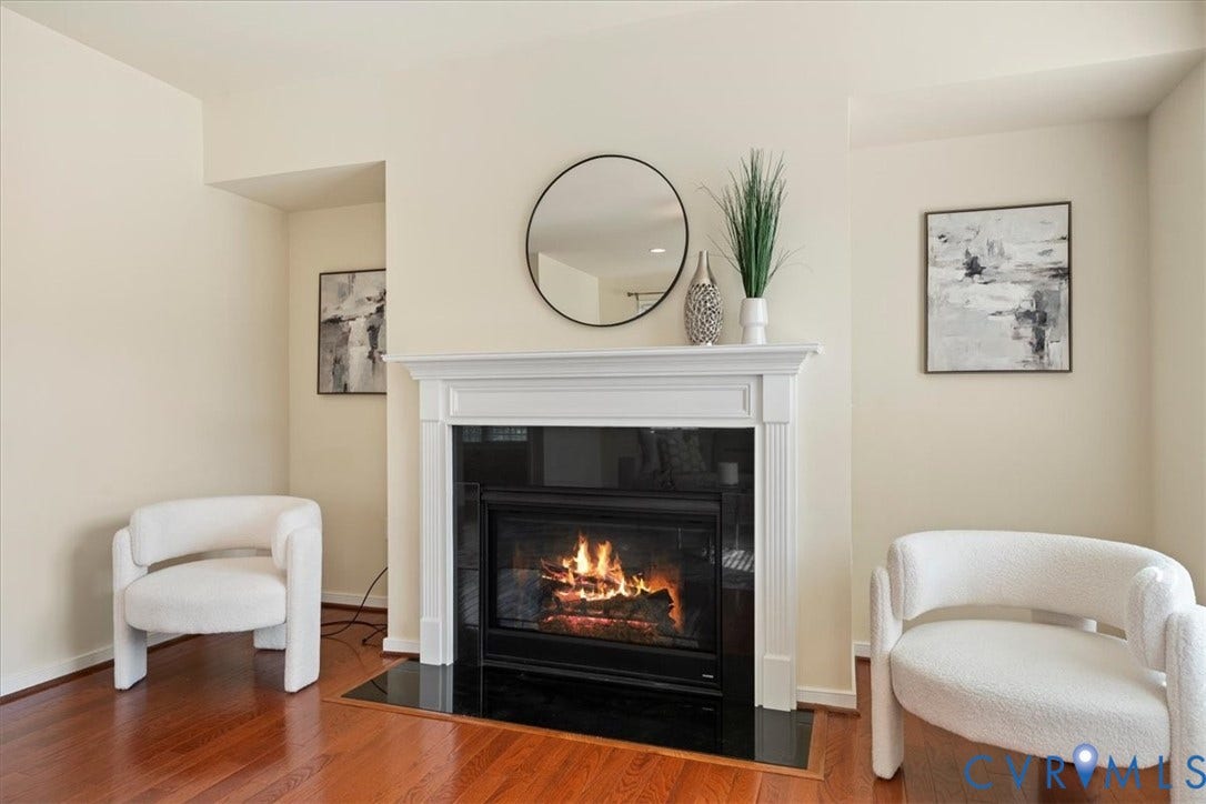 Fireplace with white mantel, black hearth, and wood-finish flooring