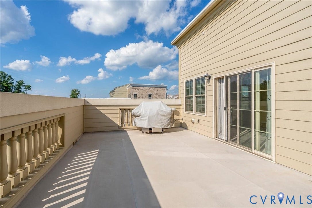 Spacious rooftop terrace with a balustrade railing, durable flooring, and direct access through a large sliding glass door