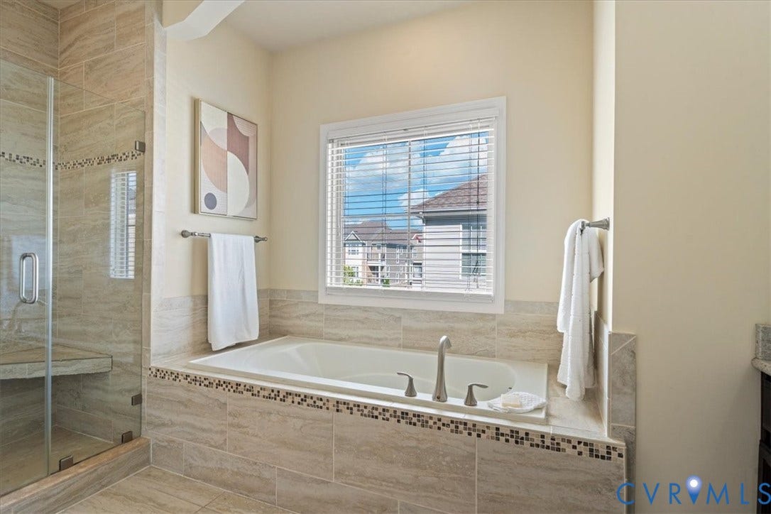 Built-in soaking tub with deck-mounted fixtures, glass-enclosed shower with tiled bench, and coordinating tile surround