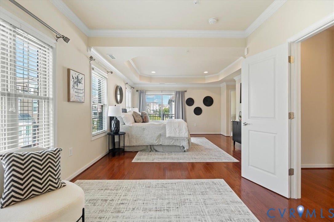 Hardwood flooring throughout, tray ceiling, crown molding, double windows with blinds, and white paneled doors