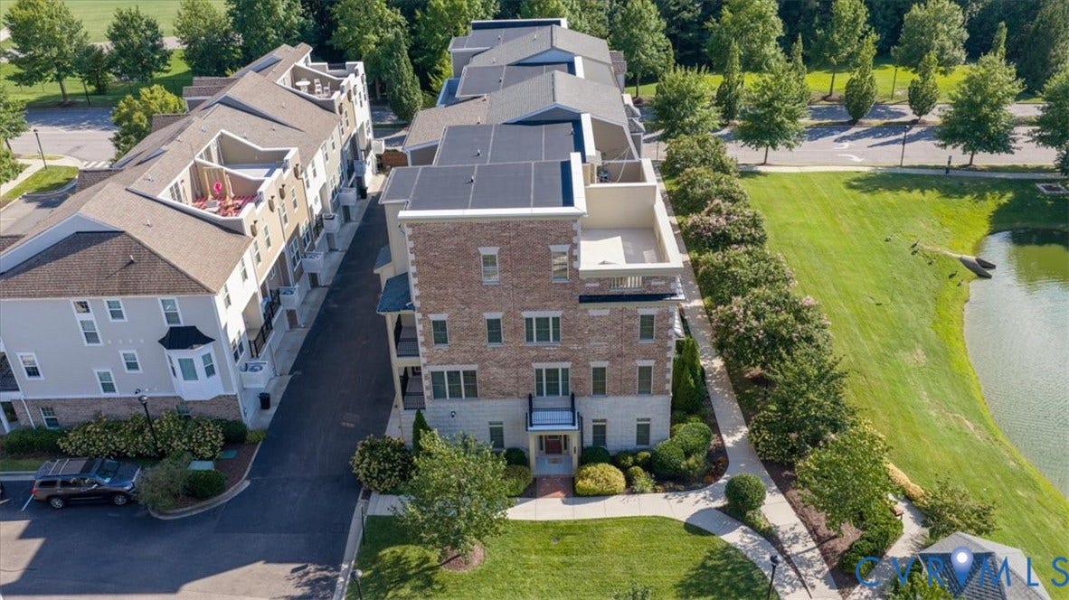Brick and siding exterior, multiple balconies, rooftop terrace, adjacent green space, and pond