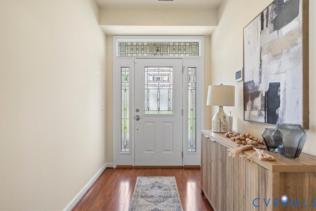 Entryway featuring a white paneled door with decorative glass inserts, sidelight windows, and a transom window