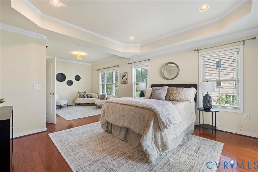 Hardwood flooring, recessed lighting, tray ceiling with crown molding, two windows with blinds, and white interior doors