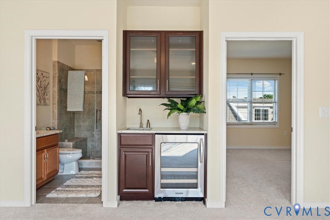 Built-in wet bar featuring dark wood-finish cabinetry, a stainless steel sink, and a built-in beverage cooler