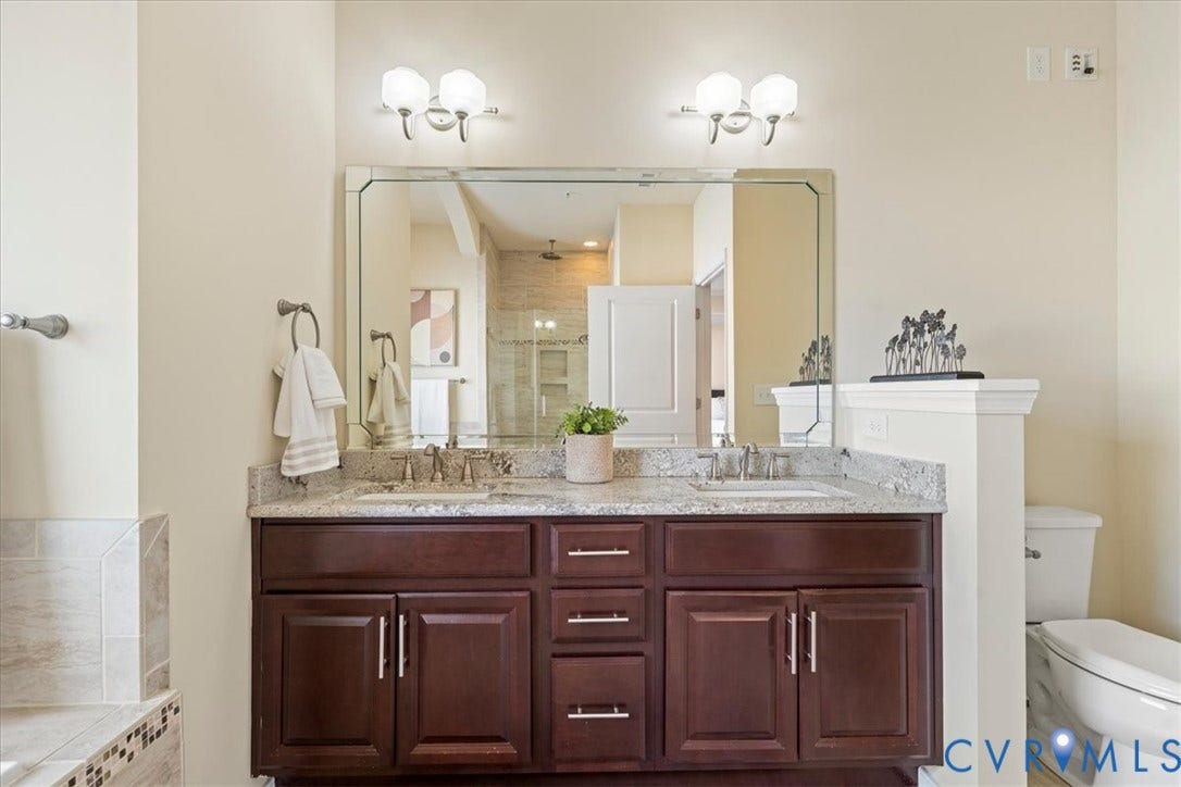 Dual vanity with a stone countertop, individual sinks, and dark wood-finish cabinetry