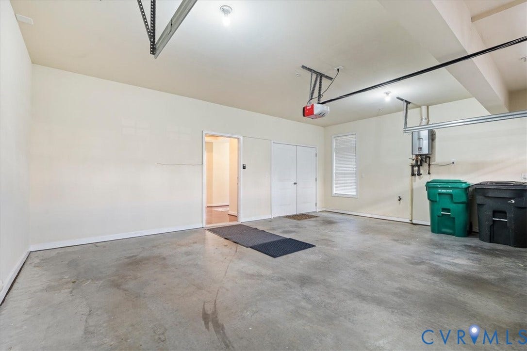 Spacious garage featuring concrete flooring, an automatic garage door opener, and a built-in water heater