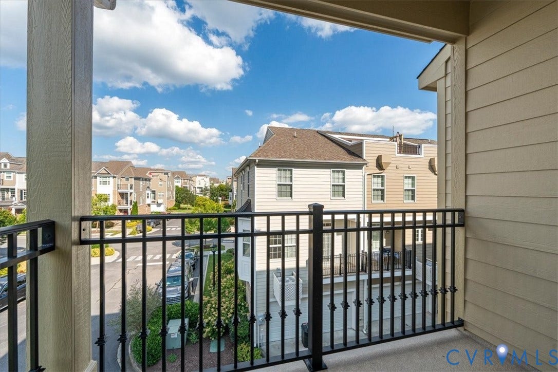Private balcony with black wrought iron railing and concrete flooring