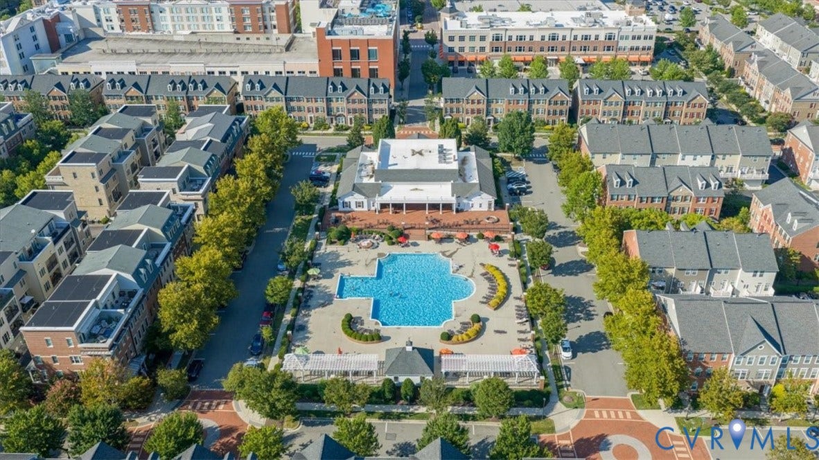 Community features a large swimming pool, expansive sundeck, central clubhouse building, and treelined streets