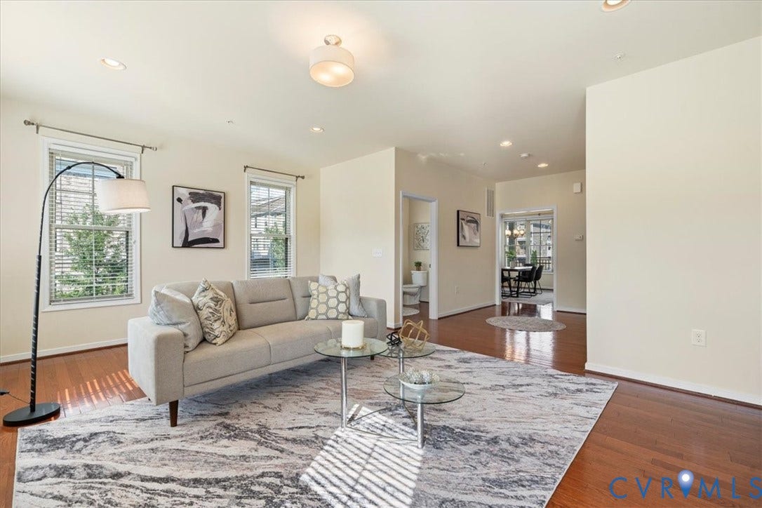 Recessed lighting, warm wood-finish flooring, and multiple windows with blinds