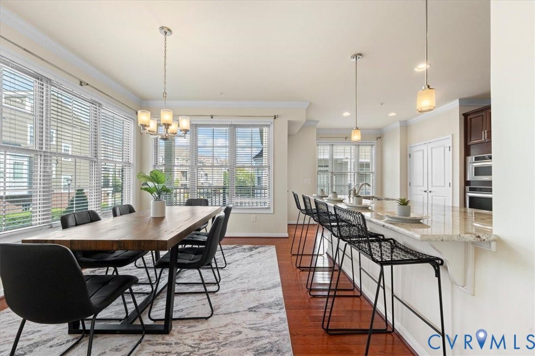 Hardwood flooring extending throughout, kitchen island with granite countertop and breakfast bar, stainless steel double ovens, and a dual-basin sink with gooseneck faucet