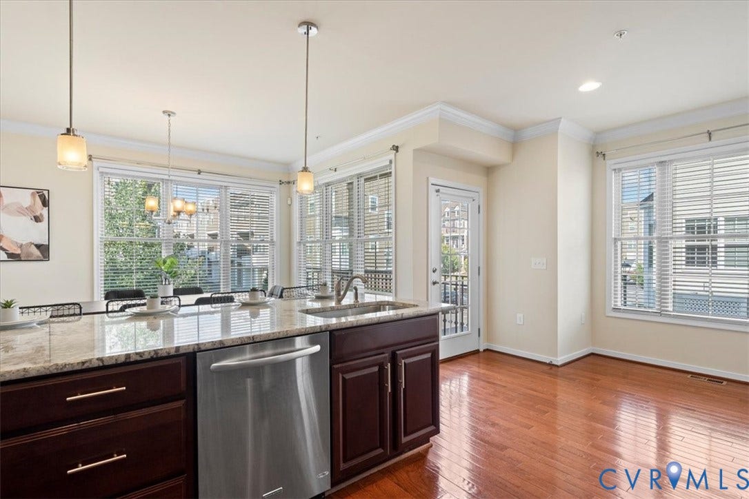 Kitchen island with light-toned countertop, stainless steel dishwasher, and dark wood-finish cabinetry