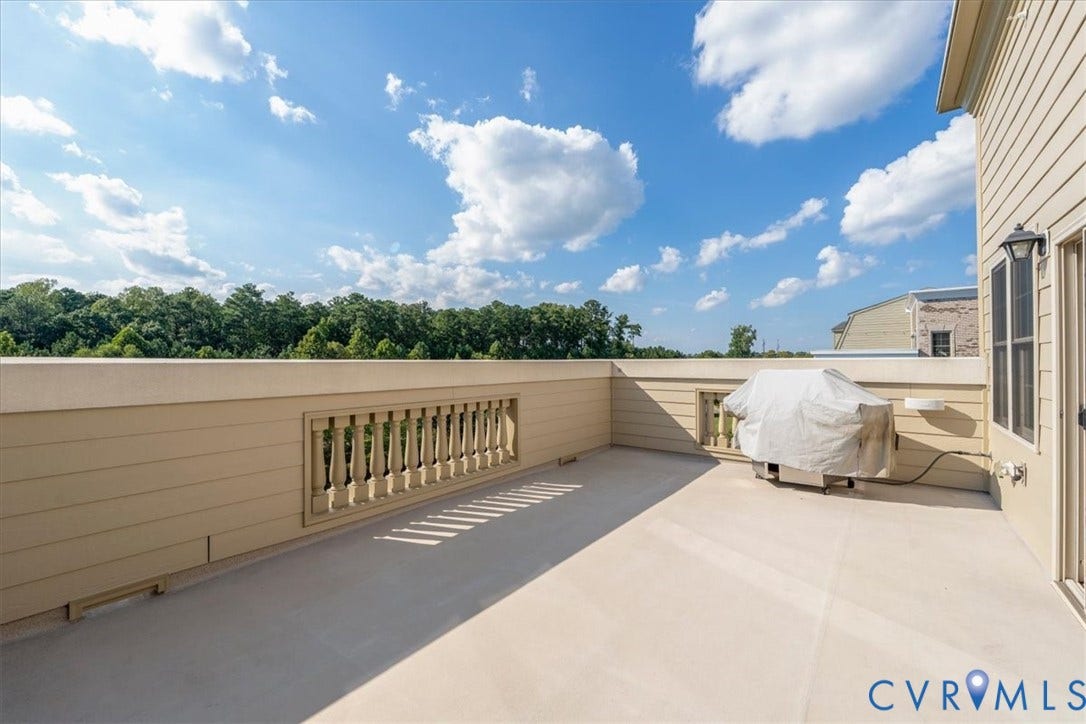 Expansive outdoor balcony with a light-colored surface, featuring a decorative balustrade and horizontal siding