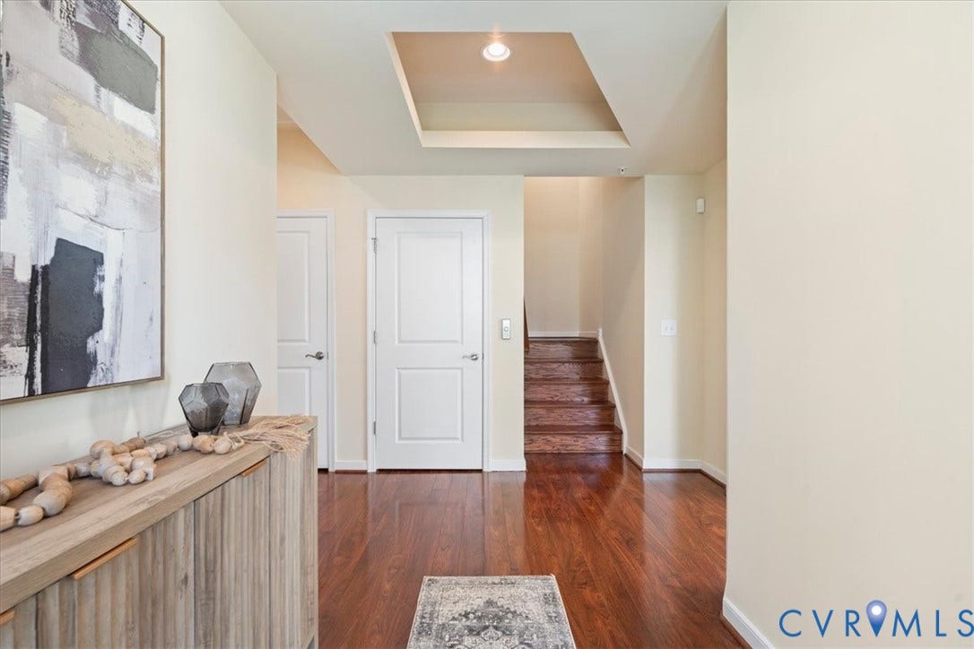 Hardwood flooring, recessed lighting, tray ceiling, white paneled doors, and wooden staircase